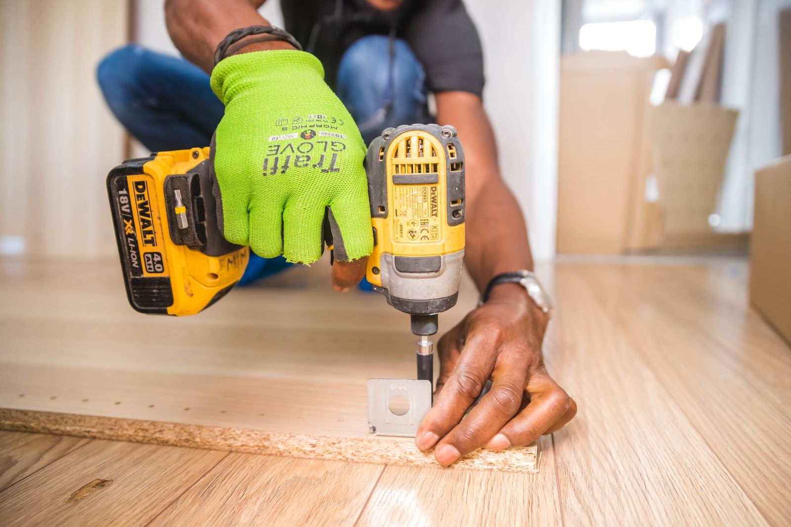 Mann arbeitet mit dem Akkubohrer auf einem Holzboden